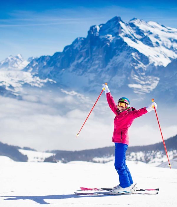 Young active woman skiing in mountains. Female skier kid with safety helmet, goggles and poles enjoying sunny winter day in Swiss Alps. Ski race for adults. Winter and snow sport in alpine resort.